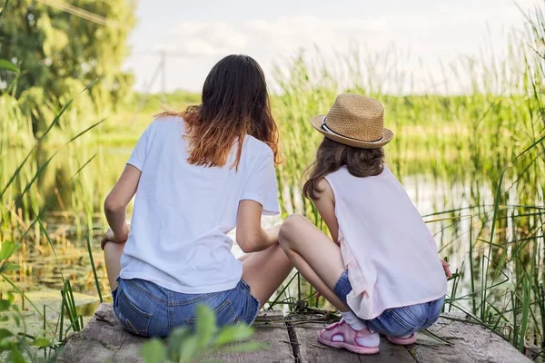 Children resting near the water on sunny summer day, back view — Stock Photo, Image