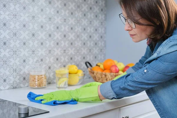 Frau in Handschuhen mit Lappen putzt Küchenarbeitsplatte — Stockfoto