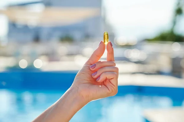Солнечный золотой витамин D капсула масла Омега-3 в руке женщины — стоковое фото