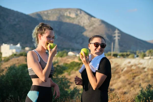 Twee vrouwen moeder en tienerdochter eten groene appels op de natuur — Stockfoto