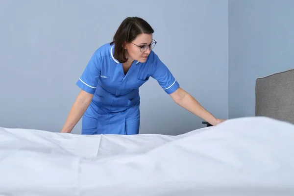 Idade média empregada feminina profissional fazendo cama no quarto do hotel — Fotografia de Stock