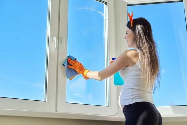 Молода вагітна жінка в рукавичках робить прибирання будинку, копіює простір — стокове фото