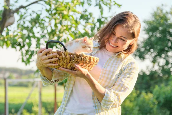 Mature smiling happy woman holding ginger kitten in basket — 图库照片