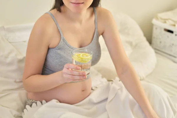 Pregnant woman drinking water with slice of lemon — Stok fotoğraf