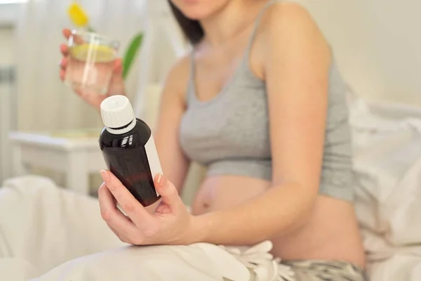 Mujer embarazada joven sosteniendo medicina soluble en su mano, vitaminas — Foto de Stock