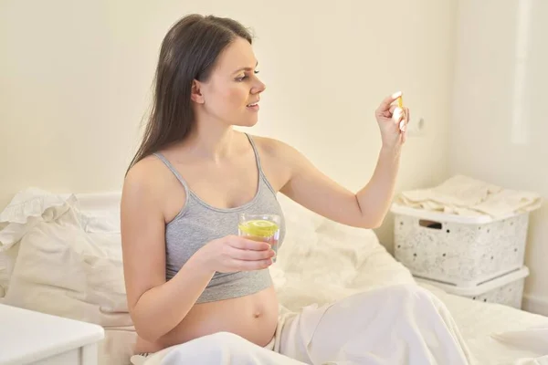 Young pregnant woman taking vitamins. A, D, E, omega-3 capsules — Stockfoto