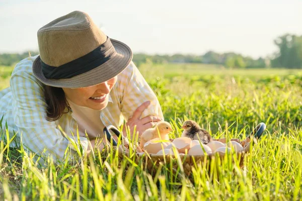 Basket with newborn chickens, happy woman in hat looking baby chicks — Stockfoto