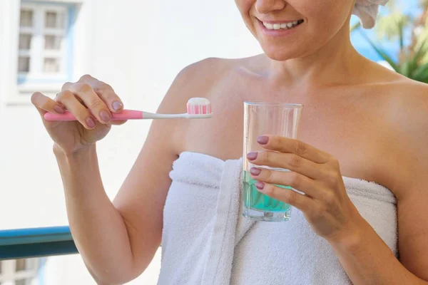 Зріла жінка чистить зуби, жінка з склянкою води — стокове фото