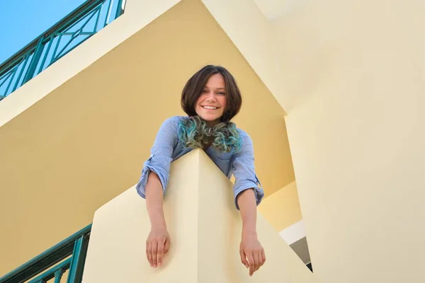 Дівчина-підліток дивиться на камеру вниз, стоячи на балконі — стокове фото