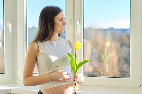 Primavera, belleza, salud, retrato de una joven embarazada con tulipán amarillo —  Fotos de Stock