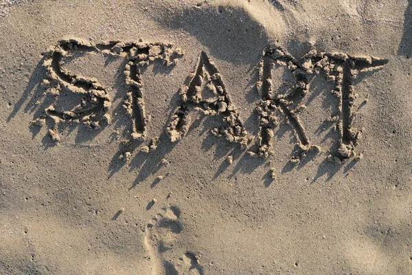 Texto de inicio escrito en arena en la playa del mar y huellas desnudas frente a la palabra —  Fotos de Stock