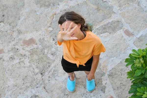 Adolescente menina acenando, acolhe, olha para a câmera, mostra Olá gesto — Fotografia de Stock