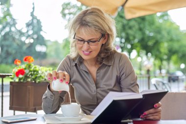 Açık bir kafede kahveli bir bardağa süt döken kadın, boşluğu kopyala.