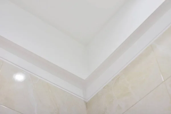 Bathroom, ceiling with moldings, beige tiles on the wall.