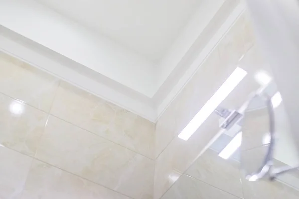 浴室のインテリア 詳細を閉じます 成形天井の一部 洗面台ミラーの上のLedライト 化粧鏡 壁にベージュ大理石のタイル — ストック写真