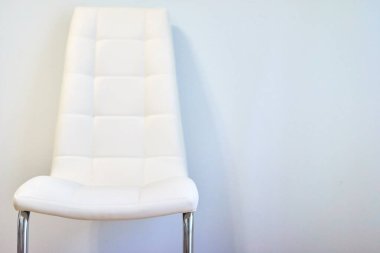 İç kısımda modern bir beyaz sandalye, arka planda ışık duvarı, kopyalama alanı