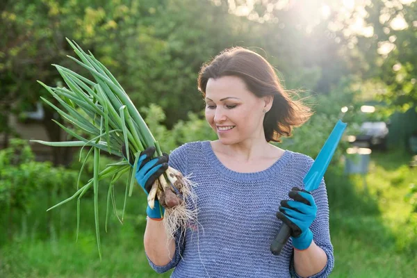 戴着手套的女人拿着一把菜刀 手里拿着一束新鲜的青葱 春天的一天 女人们在花园里散步 — 图库照片