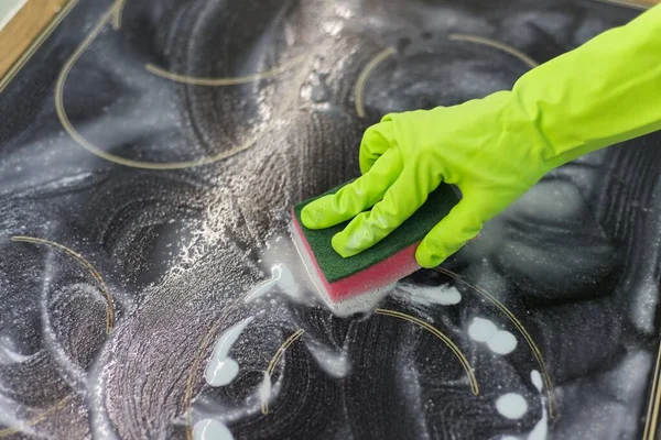 スポンジと洗剤で現代の調理ガラスセラミック電気表面を洗浄する手の女性のクローズアップ — ストック写真