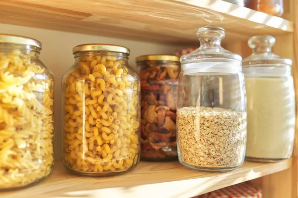 Wooden shelves in pantry for food storage, grain products in storage jars.