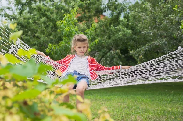 美丽的女孩躺在吊床上 笑着让孩子在春天的花园里休息 复制空间 — 图库照片