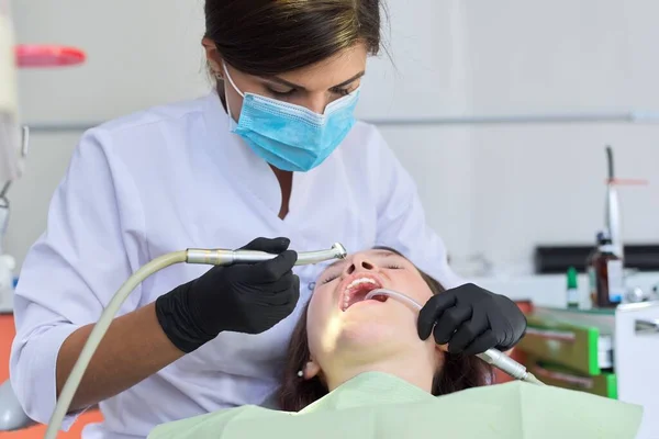 Woman doctor dentist treating teeth to girl patient in dental office — Stock Photo, Image