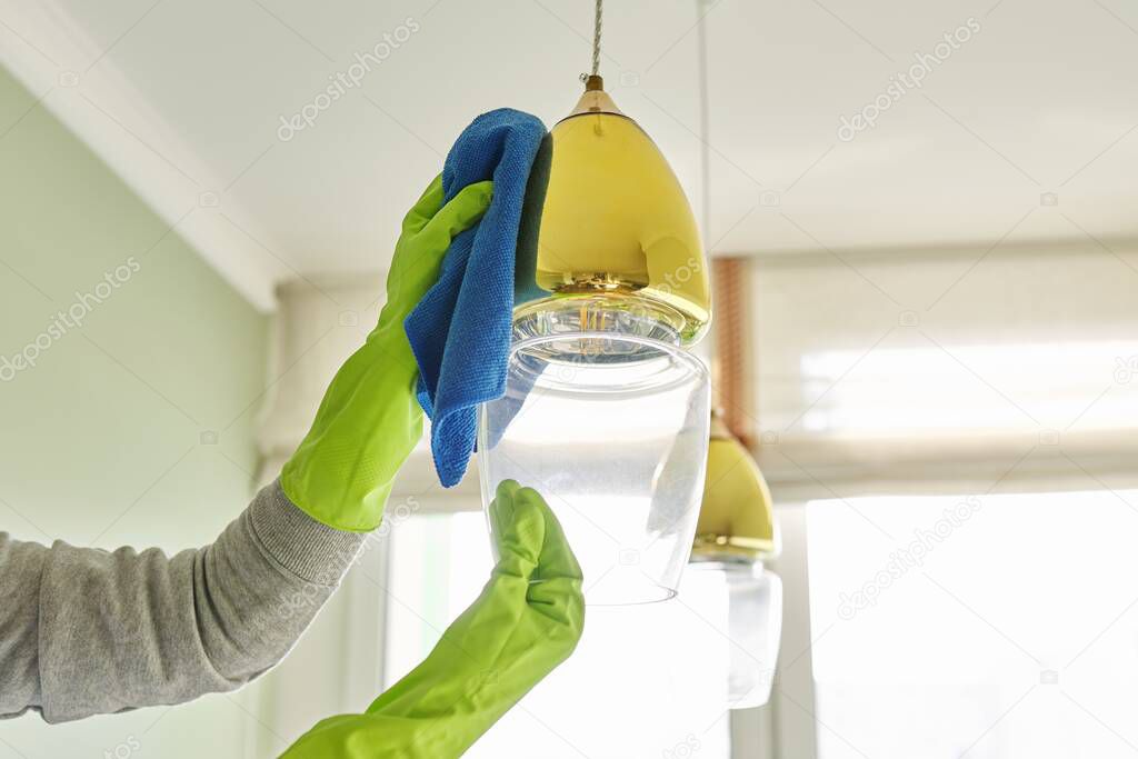 House cleaning, close-up of hands with rag detergent, cleaning and polishing lamp, chandelier