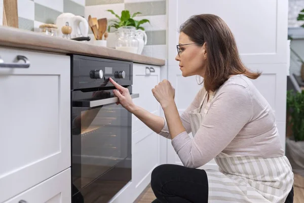 Mulher Madura Avental Perto Forno Cozinha Dona Casa Ligando Configurações — Fotografia de Stock