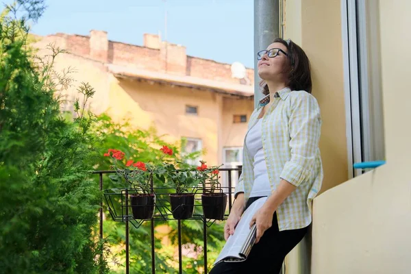 Vacker mogen kvinna i hemkläder på öppen balkong läsa tidningen — Stockfoto
