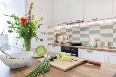 Evde yemek pişirmek, salata için sebzeler, mutfak mobilyaları.