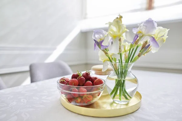 ホームダイニングルームのインテリア、花瓶に虹彩の花束、イチゴとトレイ — ストック写真