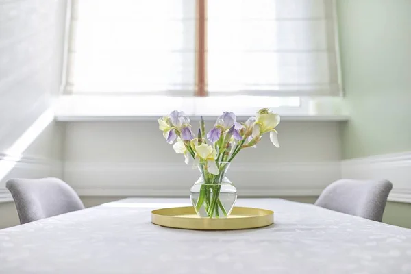 Wazon z bukietem żółtych i fioletowych tęczówek na stole przy oknie — Zdjęcie stockowe