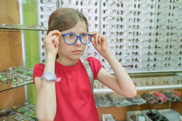 โชว์เคสที่มีแว่นตาในร้านแว่นตา เด็กผู้หญิงในแว่นตา — ภาพถ่ายสต็อก