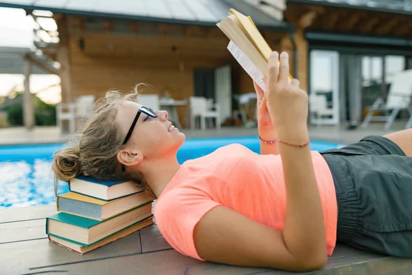 Chytrý dospívající dívka v brýle čtení knihy, teenager poblíž domu — Stock fotografie