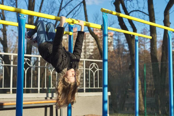 Girl child hanging upside down on outdoor sports playground with eyes closed — Stock Photo, Image