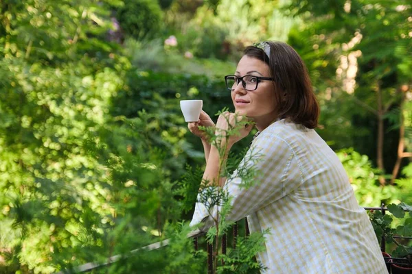 Красивая зрелая женщина в домашней одежде на открытом балконе с чашкой кофе — стоковое фото