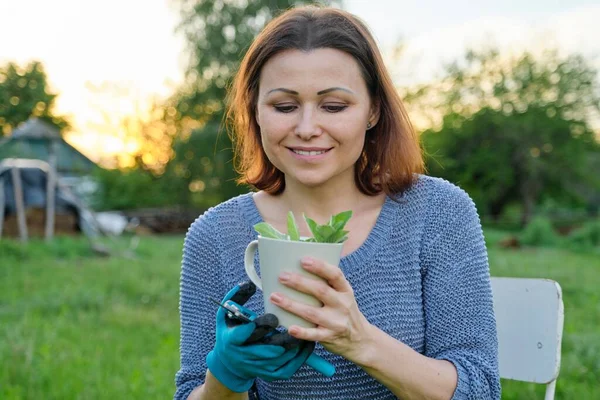 Красива зріла жінка садівник в рукавичках з секаторами з чашкою трав'яного чаю — стокове фото