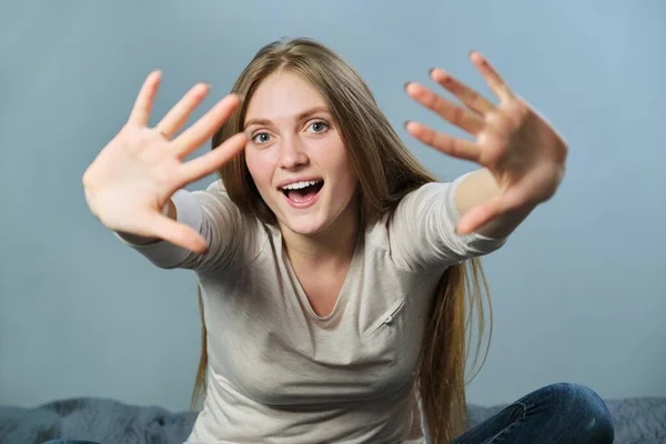 Porträt einer jungen schönen, positiv lächelnden Frau, die mit den Armen wedelt und in die Kamera blickt — Stockfoto