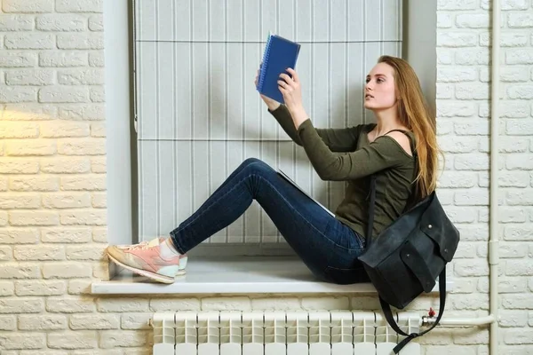 Étudiante assise sur le rebord de la fenêtre, étudiant, lisant un cahier — Photo