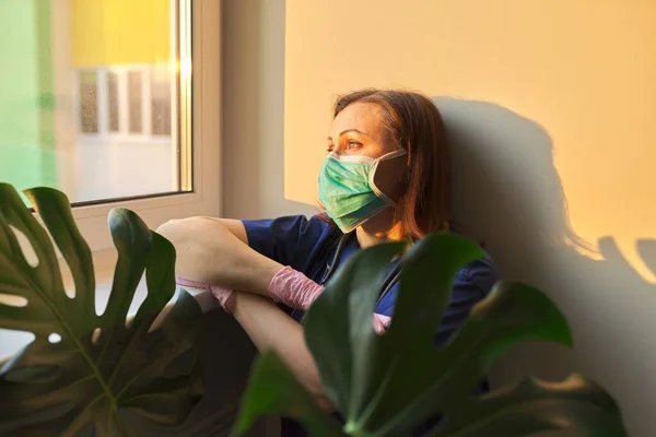 Retrato de la mujer doctora usando mascarilla médica, mirando a la ventana de la clínica —  Fotos de Stock