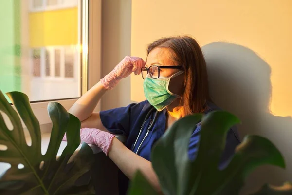 Retrato de la mujer doctora usando mascarilla médica mirando a la ventana de la clínica —  Fotos de Stock