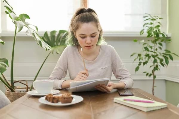 Dospívající dívka sedí doma u stolu psaní lekce pomocí smartphone pro učení — Stock fotografie