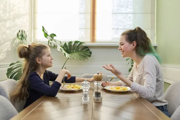 Children two girls eat lunch sitting at table in home kitchen, homemade food