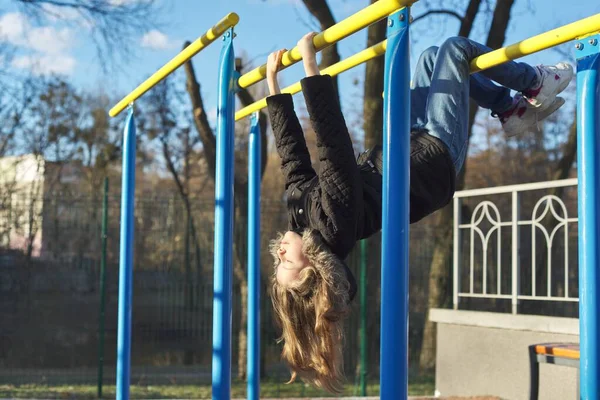 Girl child hanging upside down on outdoor sports playground with eyes closed — Stock Photo, Image