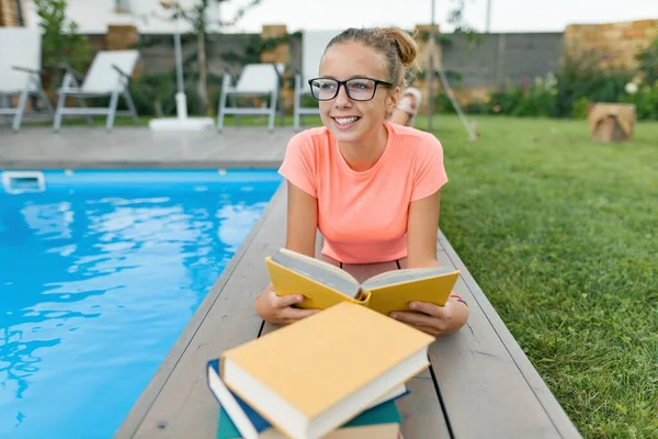 Chytrý dospívající dívka v brýle čtení knihy, teenager poblíž domu — Stock fotografie