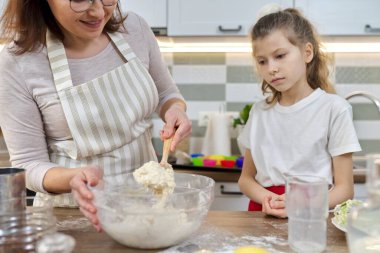 Anne ve kızı mutfakta hamur yoğuruyorlar, yakın plan.