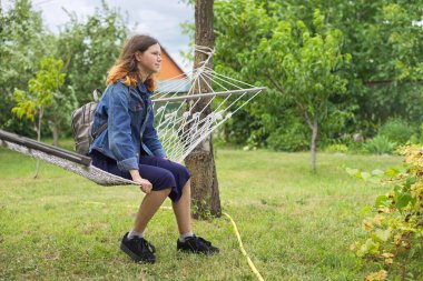 Güzel genç kız bahçede hamakta dinleniyor, arka plan yeşil çimenler, ağaçlar, fotokopi alanı