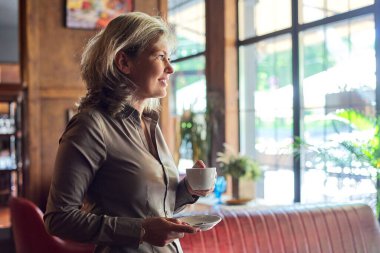 Lokantada kahve içen olgun, güzel bir kadın. İş kadını molada dinleniyor, boşluğu kopyala