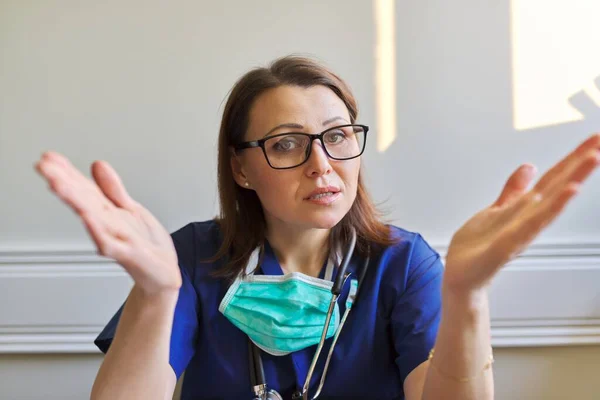穿着蓝色制服 戴着听诊器面罩的会说话的女医生的画像 坐在办公室 视频电话会议 在线医疗咨询和援助 — 图库照片