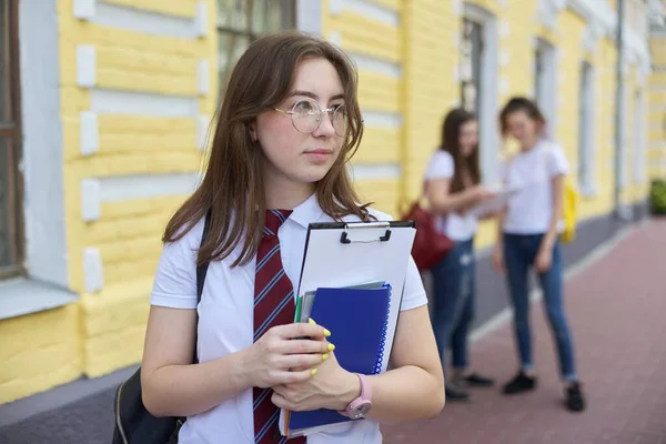 戴眼镜的女学生形象地把白色T恤和背包绑在一起 背景黄色砖楼 学生群 — 图库照片
