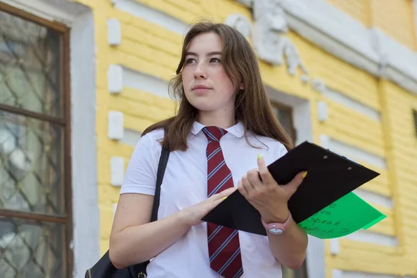 十几岁的女大学生穿着白色T恤 打领带 做背景砖建筑 在户外摆姿势 开始上课 回到大学 — 图库照片